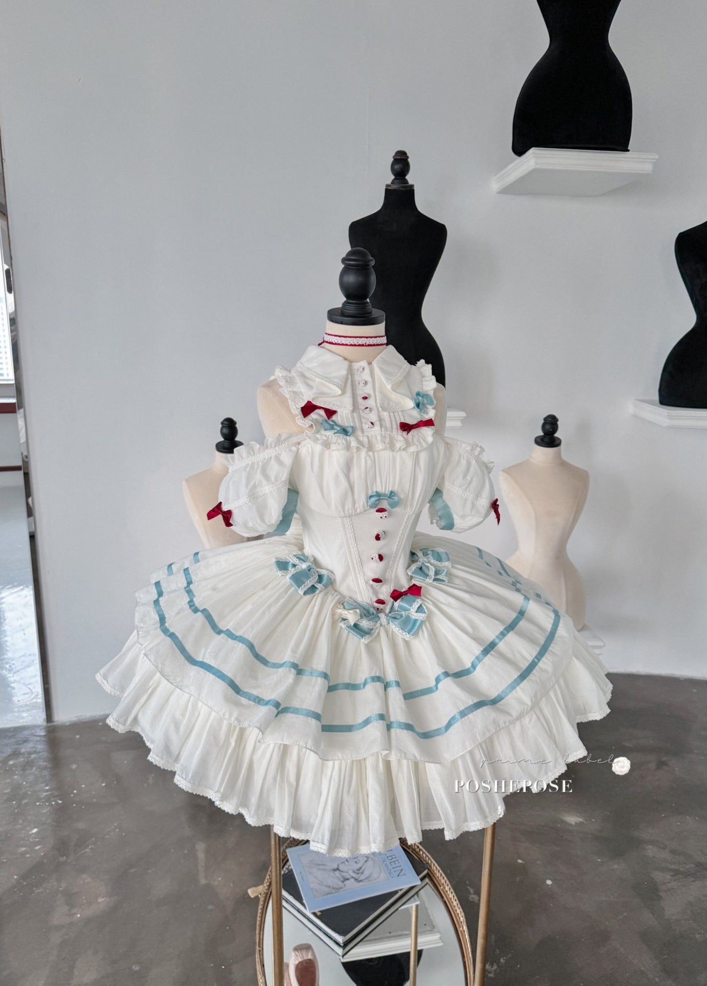 White Lolita dress with blue accents and delicate ruffled layers.