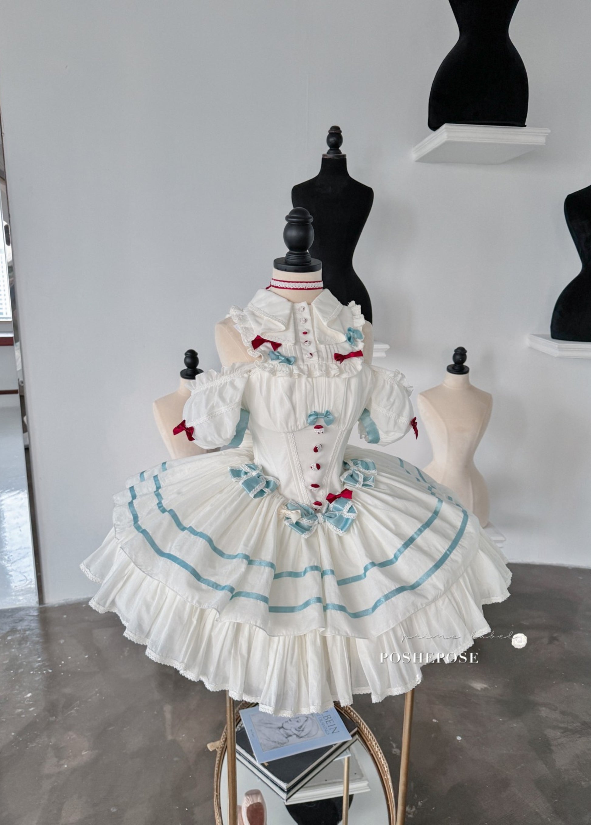 White Lolita dress with blue accents and delicate ruffled layers.